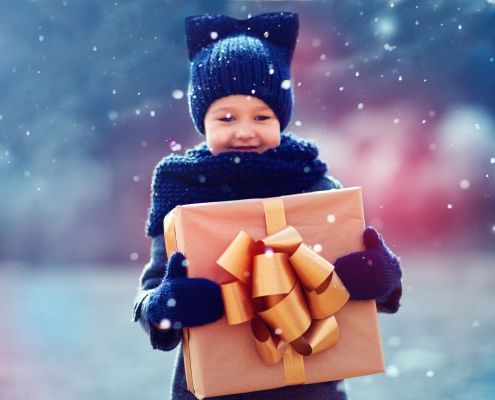 winters weert inpakatelier adorable kid with big gift box under a snowfall. Focus on gift box